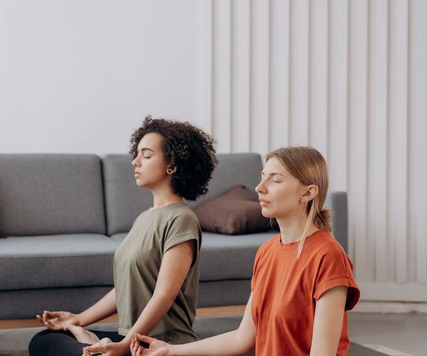 A person sitting in a calm meditation pose in a bright room.